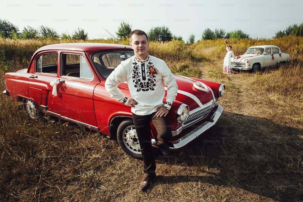 stylish bride and happy groom near  two retro cars on the background of nature