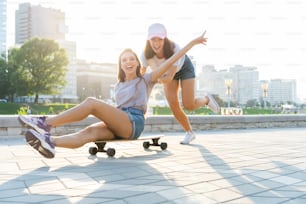 公園でスケートボードに乗って楽しそうにしている笑顔の若い女の子2人