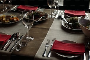 expensive catering at restaurant for celebrations. luxury glasses and plates with napkins on stylish decorated table at wedding reception. transparent glass and silver cutlery