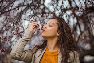 자연의 향기. 공원에서 꽃 냄새를 맡는 아프리카계 미국인 여성.