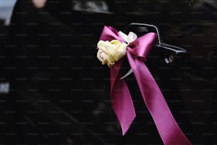 elegant luxury black car decorated with roses and purple ribbons for a wedding