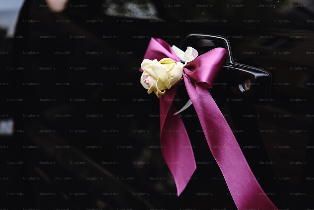 elegant luxury black car decorated with roses and purple ribbons for a wedding
