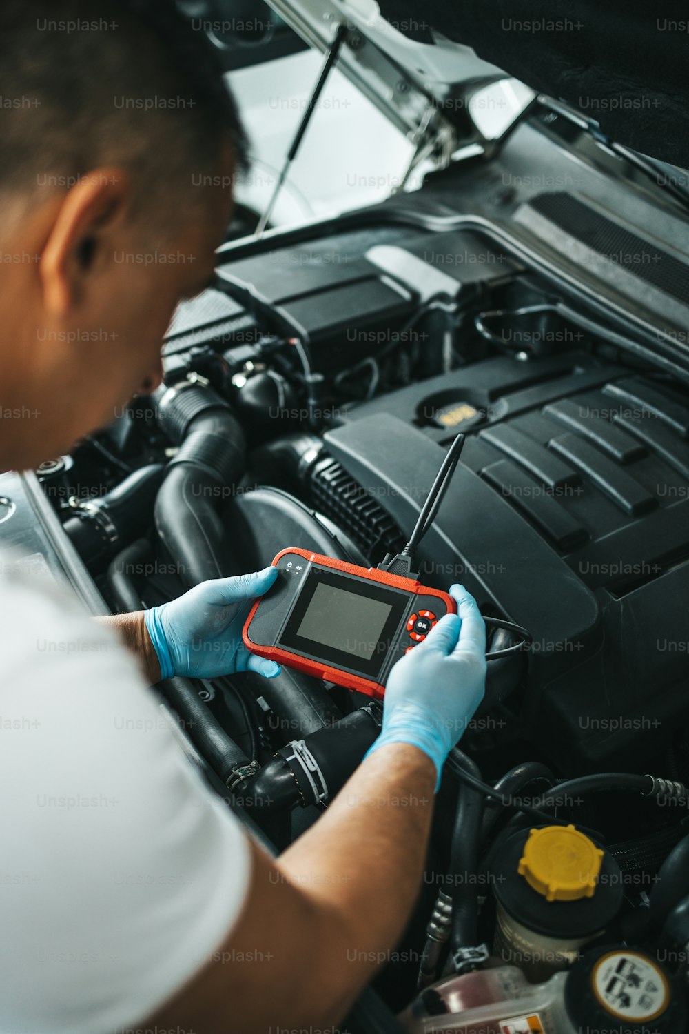 Close up shot of car mechanic using laptop computer for error tracing and diagnostic.