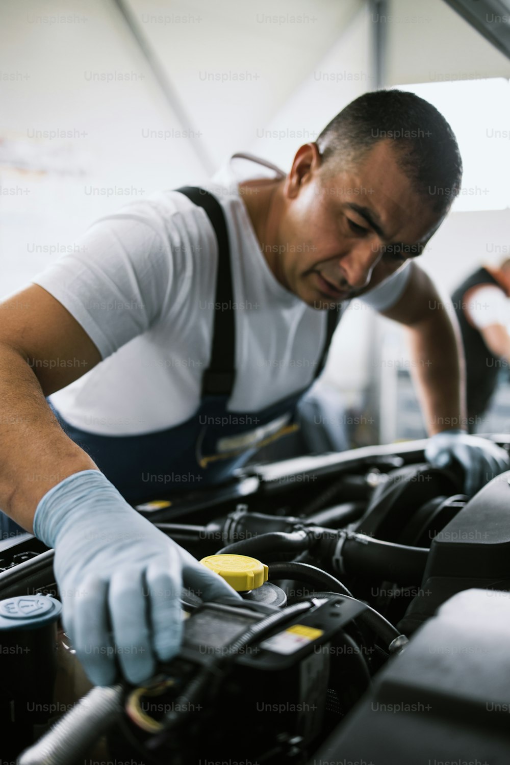 Car service mechanic worker standing in front of car engine open hood and working