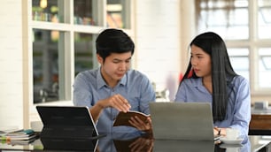 Cropped image of business developer team discussing/talking/working together with computer tablet, laptop and document while sitting at the modern working desk over comfortable office as background.