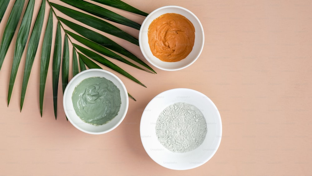 Natural SPA cosmetics for skincare, body and hair care concept. Top view facial clay masks and tropical leaf