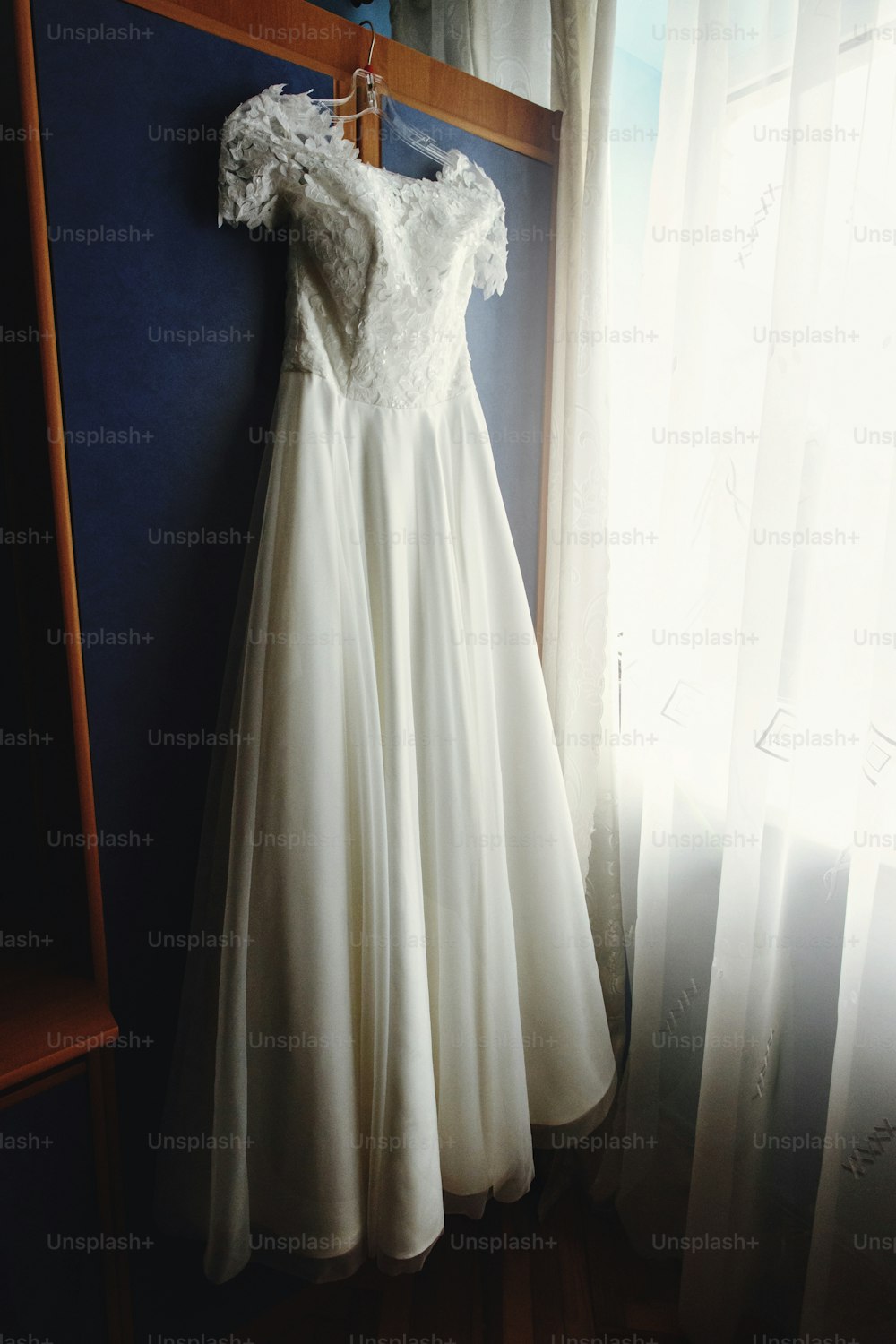 hermoso vestido de novia de lujo blanco en percha en el fondo de una ventana