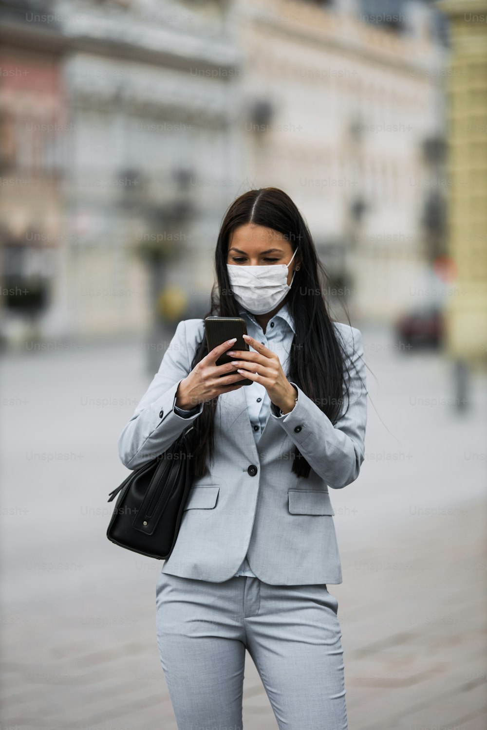 Young and elegant business woman walking on empty city street and wearing protective mask to protect herself from dangerous flu or virus. Corona virus or Covid-19 concept.