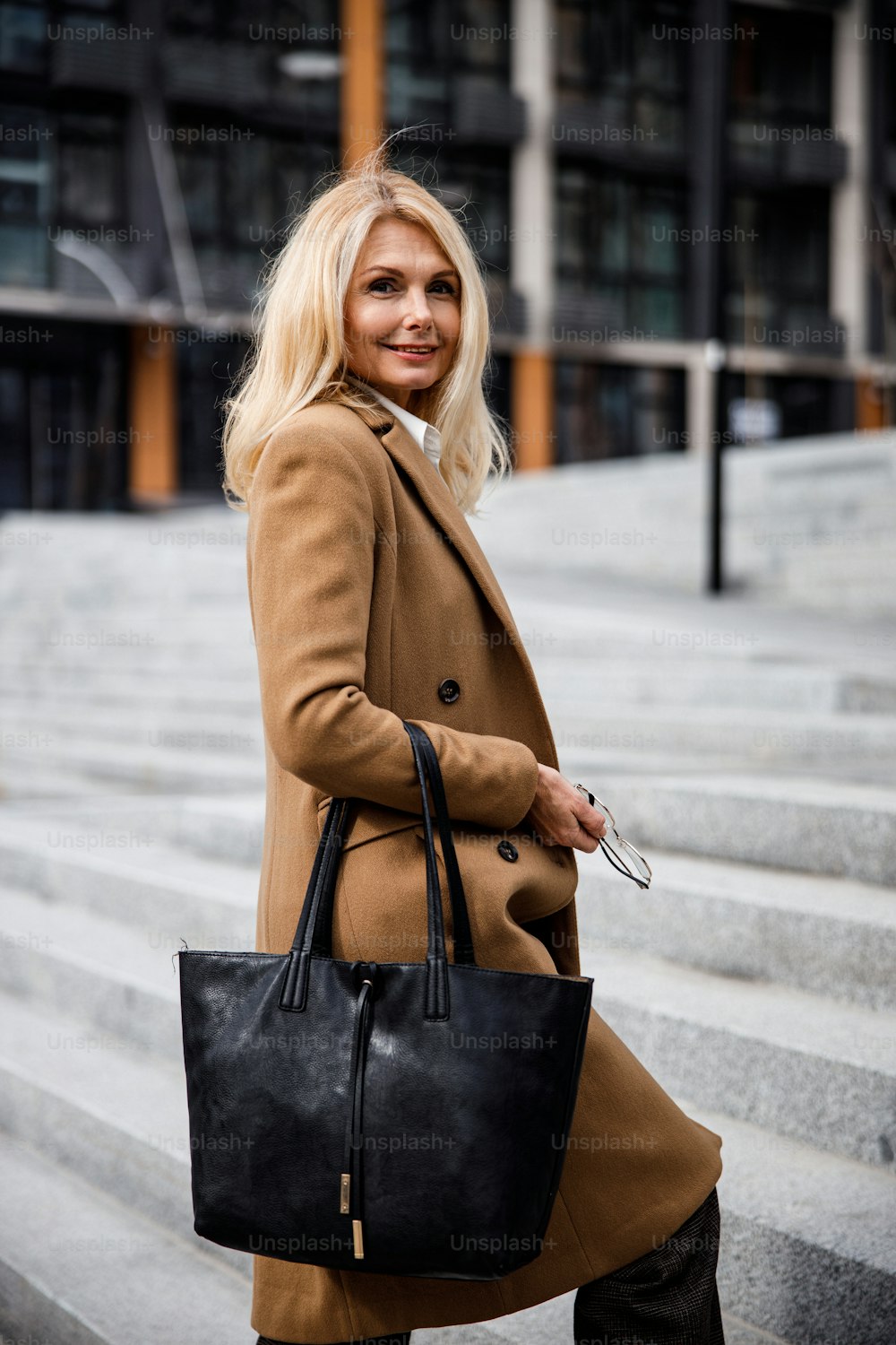 Sorridente senhora de negócios caucasiana moderna de meia-idade com uma sacola de couro posando para a câmera