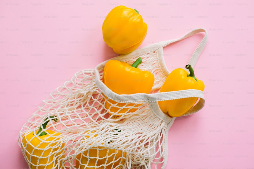 Paprika in wiederverwendbarer Tragetasche auf rosa Hintergrund flach legen. Zero Waste Shopping, plastikfrei. Lebensmittel online einkaufen. Bestellen Sie frische Bio-Lebensmittel und lassen Sie sie sicher liefern. Bleiben Sie zu Hause