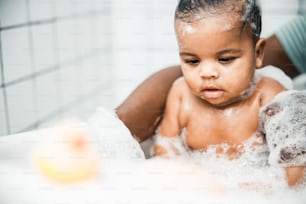 「浴室で愛らしい女の赤ちゃんを洗う父の手の接写」の写真素材。ウェブサイトのバナー