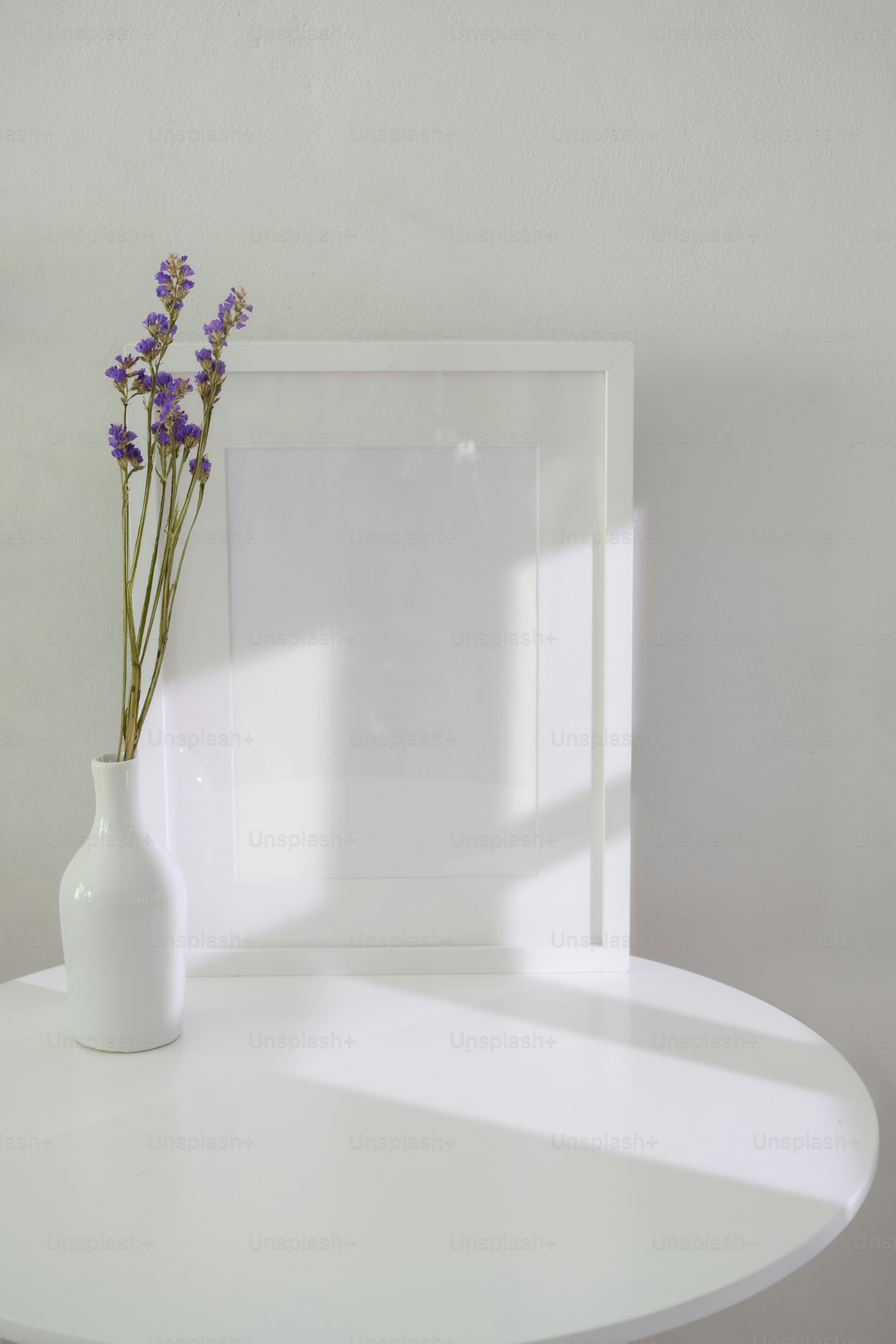 Minimal home interior design of living room with ceramic vase, mock-up frame and copy space on white circle table with white wall
