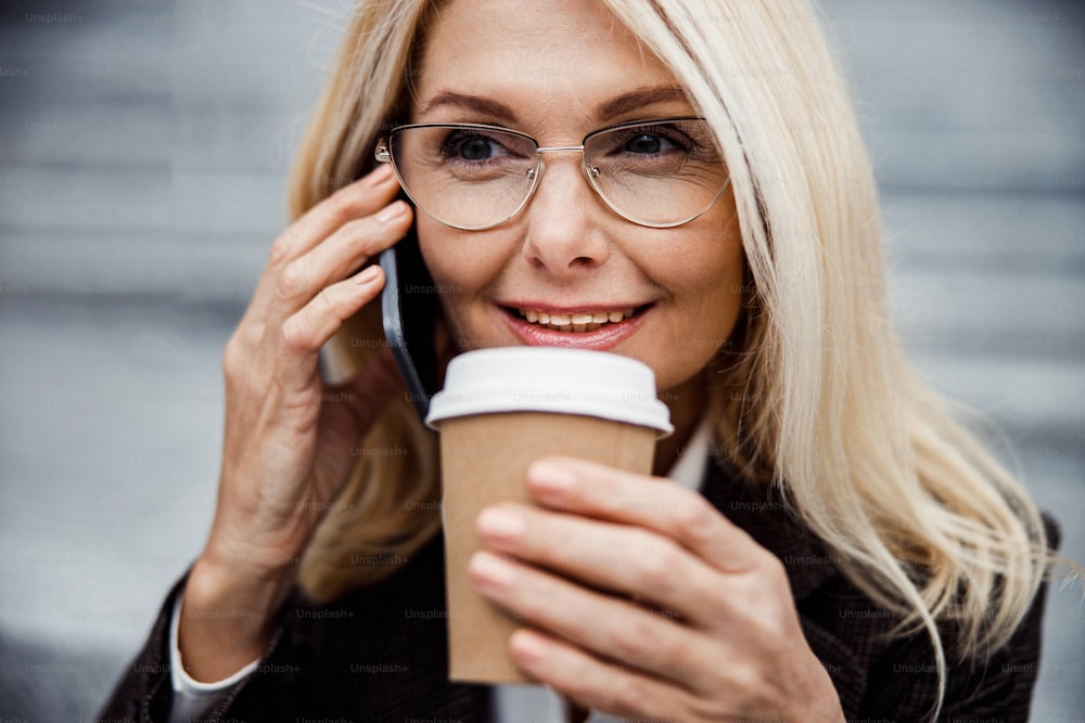 Closeup portrait of a smiling elegant Caucasian woman holding a disposable cup in her hand
