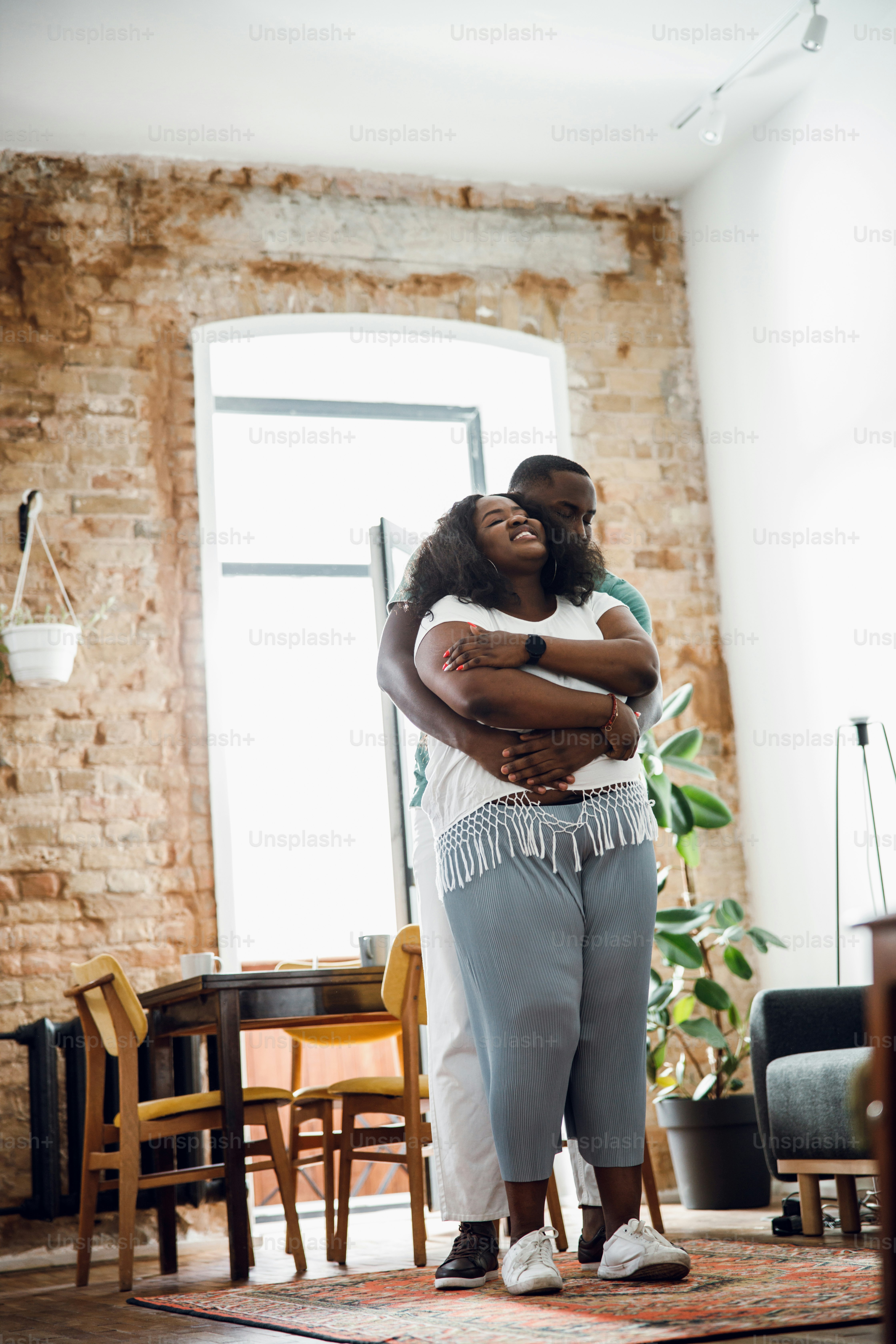 Delighted woman standing and smiling while boyfriend hugging her