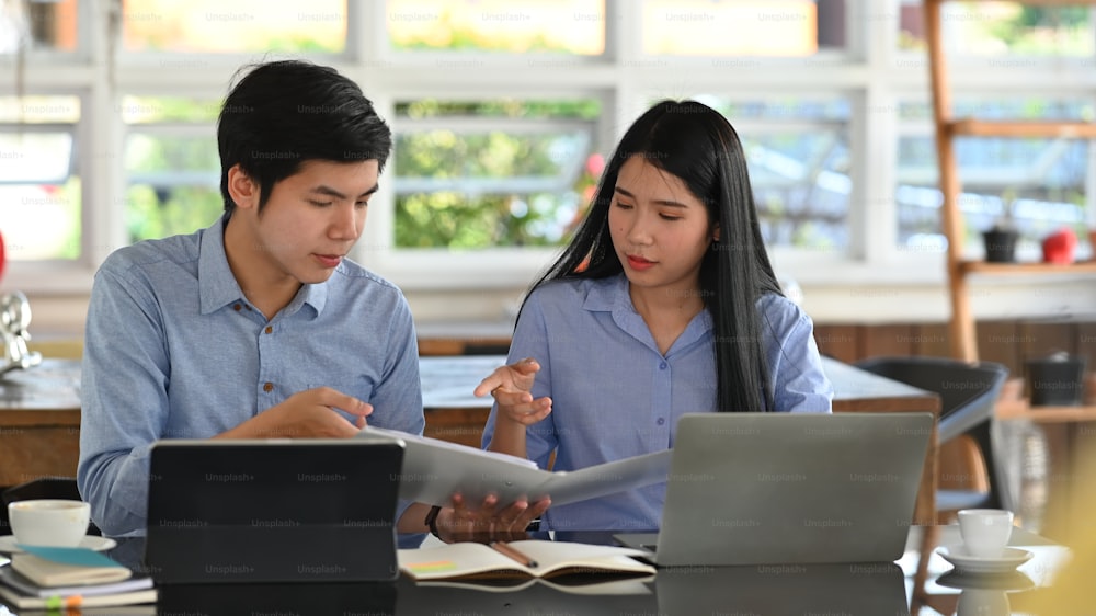 Cropped image of business developer team discussing/talking/working together with computer tablet, laptop and document while sitting at the modern working desk over comfortable office as background.