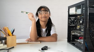Adorable school girl learning to fix a computer hardware that putting on white working desk with screwdriver and technician equipment over white isolated wall as background.