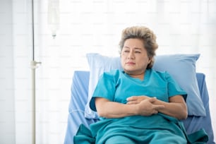 Elderly female patients sitting and looking outside with loneliness, On the bed in the hospital