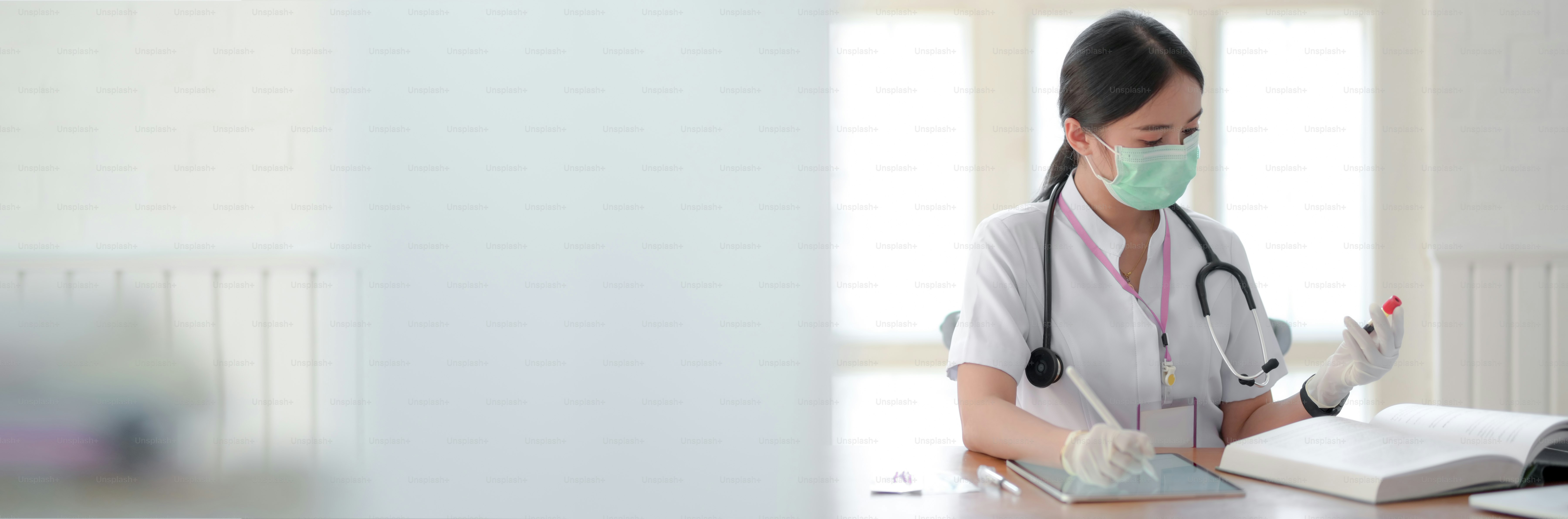 Cropped shot of female doctor analysing test tube and looking for Information in a Medical Book while sitting in examination room