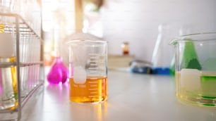 Photo de l’équipement scientifique et de la verrerie de chimie s’assemblant sur un bureau de travail blanc sur un mur blanc de laboratoire comme arrière-plan.