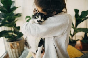 귀여운 고양이를 껴안고 있는 힙스터 소녀, 코로나바이러스 격리 기간 동안 집에 함께 앉아 있습니다. 집에 안전하게 머물러 라. 바이러스 전염병을 예방하기 위해 집에서 격리. 현대 방에 고양이와 젊은 여자