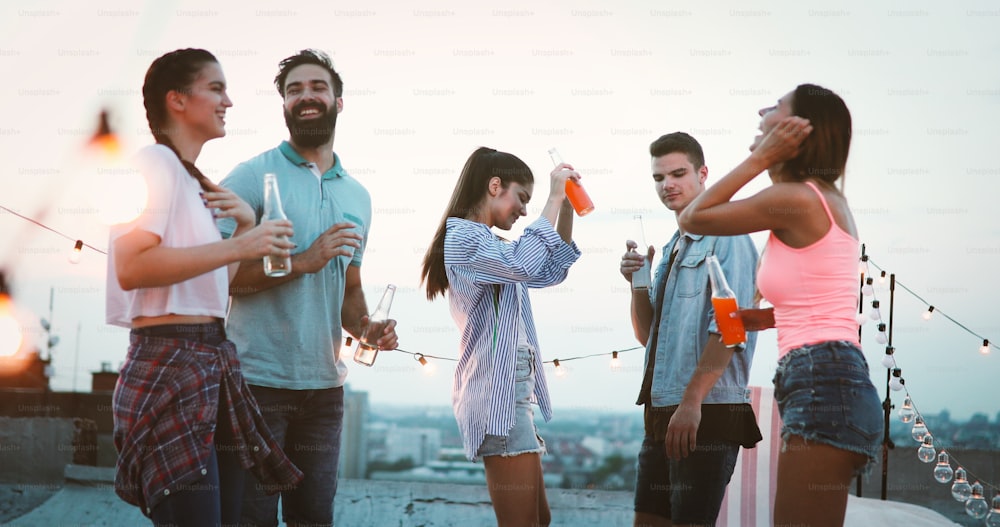 Grupo de amigos felizes tendo festa no telhado ao ar livre