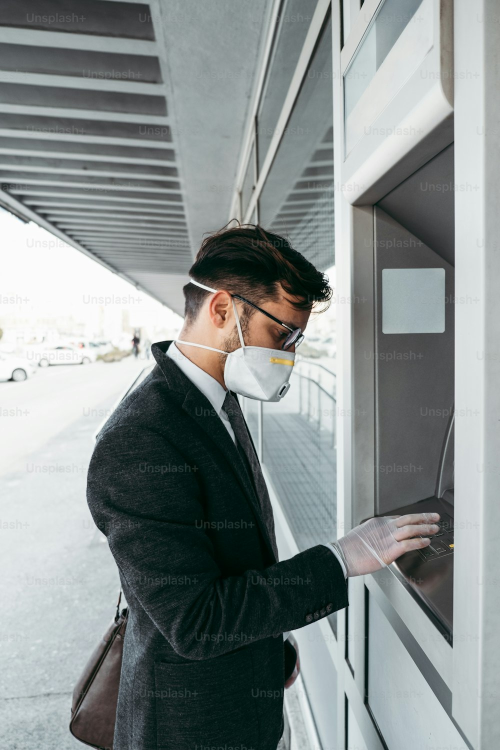 Business man with protective face mask and gloves using street ATM machine. Virus pandemic or epidemic concept.