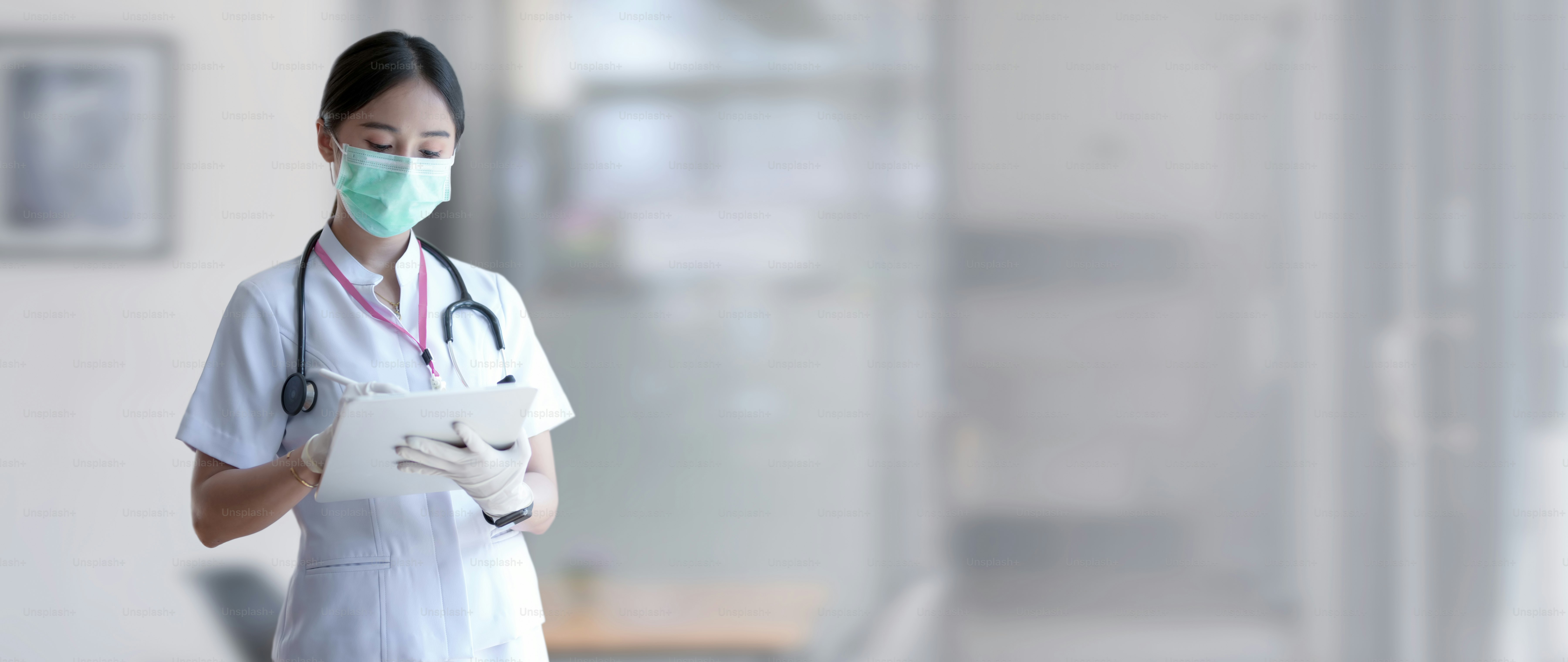 Cropped shot of female doctor analysing patient chart on digital tablet in blurred examination room background