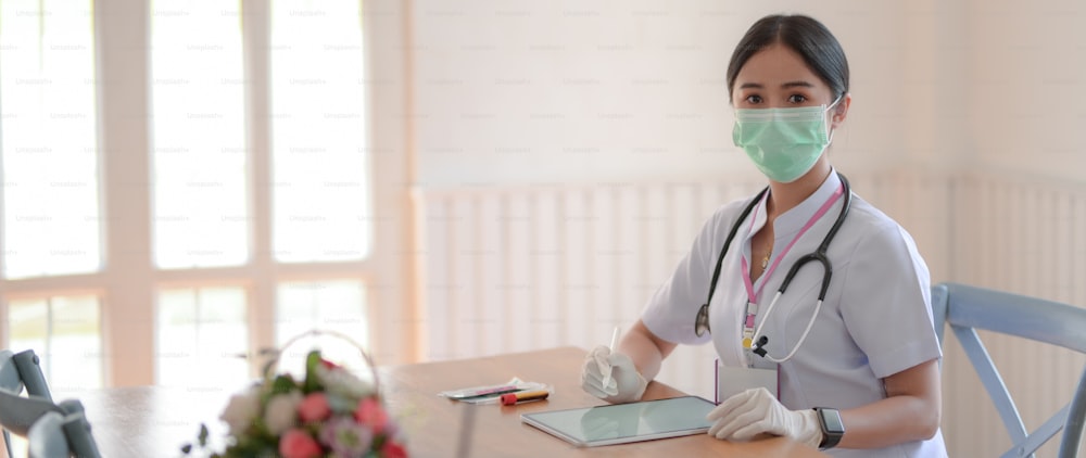 Cropped shot of female doctor reading patient chart on digital tablet while sitting in examination room