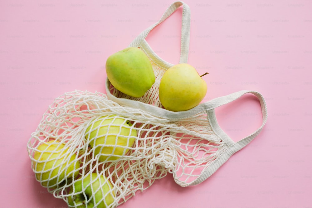 Zero Waste Shopping, plastikfrei. Äpfel in wiederverwendbarer Tragetasche auf rosa Hintergrund flach legen. Lebensmittel online einkaufen. Bestellen Sie frische Bio-Lebensmittel und lassen Sie sie sicher liefern. Bleiben Sie zu Hause