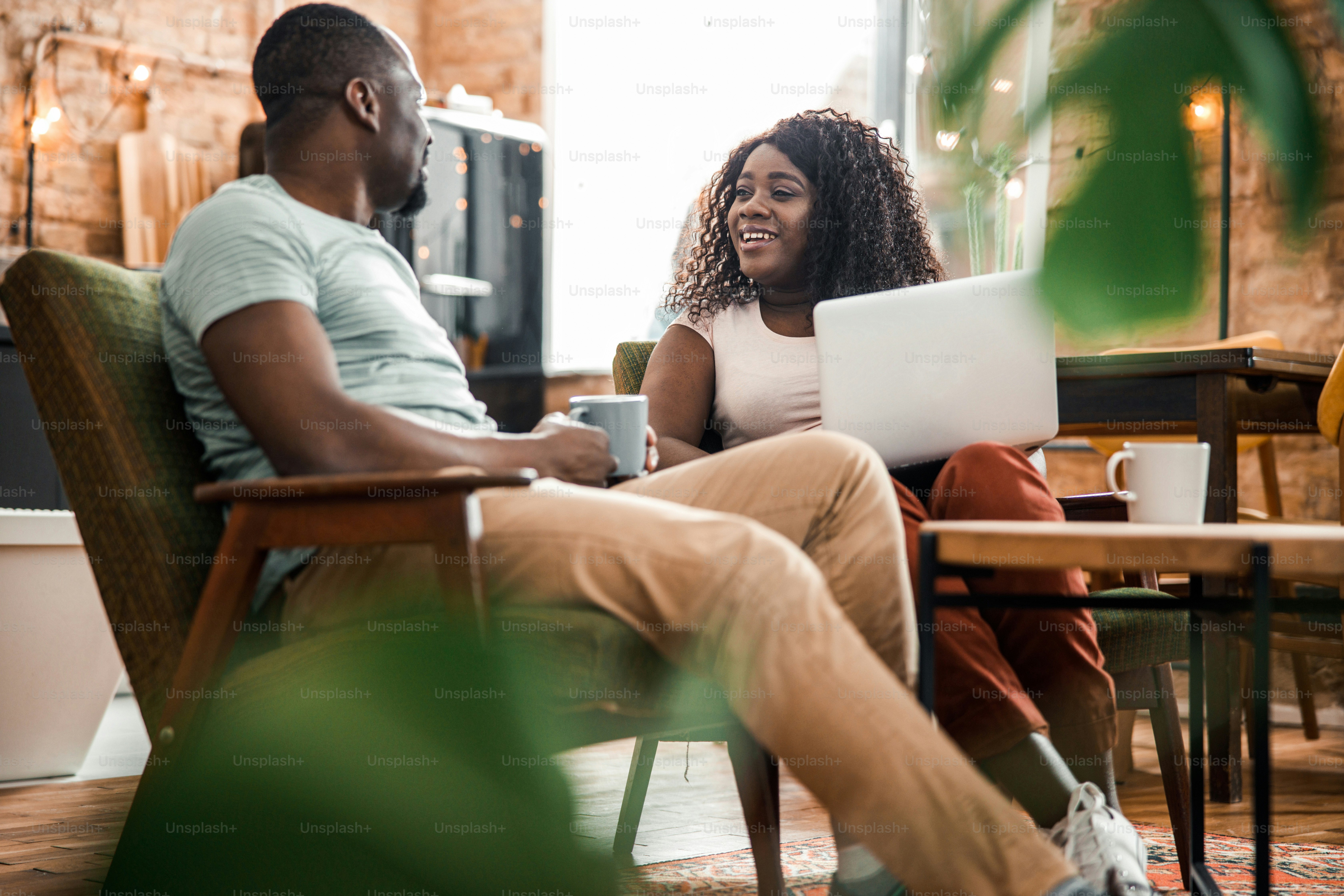 Smiling young woman using laptop and talking with husband stock photo