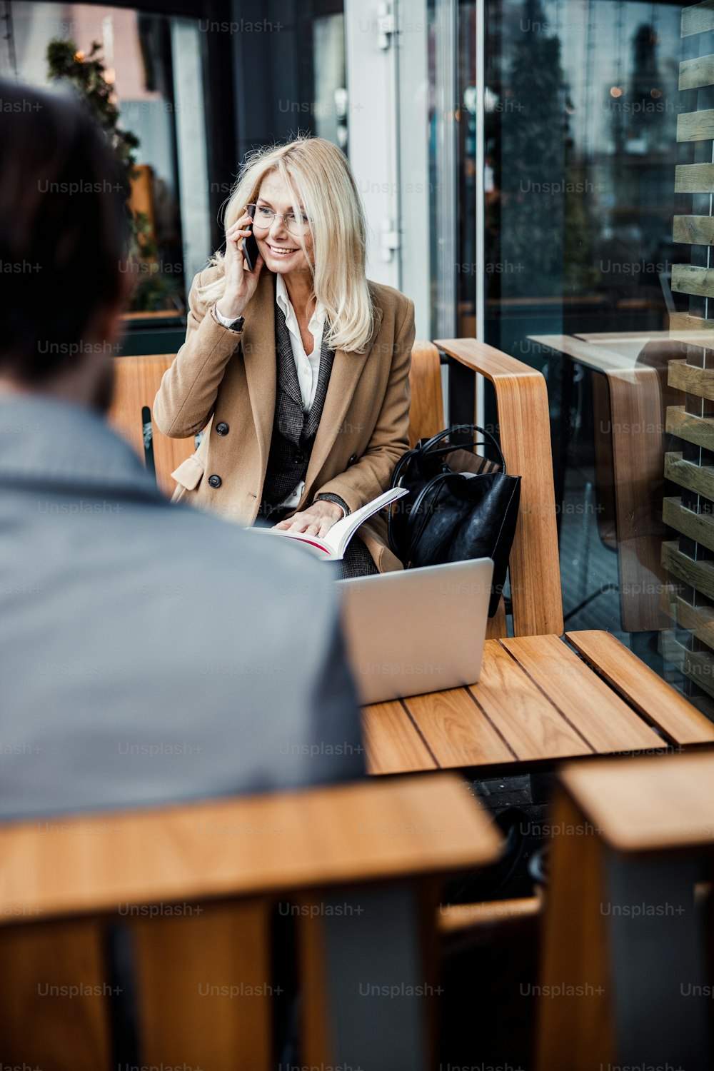 Cheerful stylish business lady with a cellphone sitting in front of a dark-haired Caucasian man