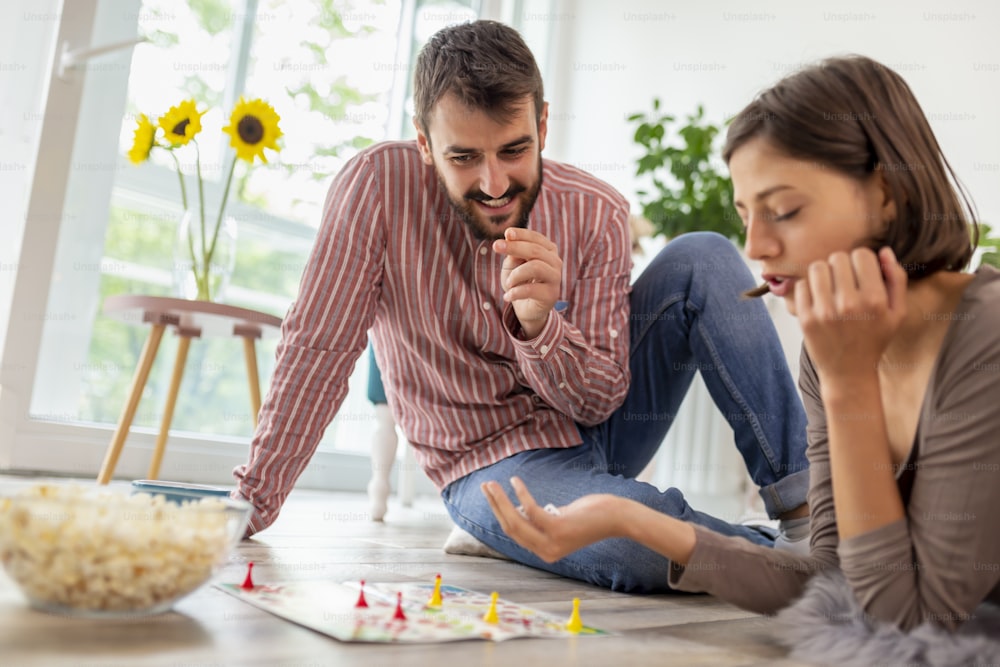 Couple in love enjoying their time together, eating popcorn and having fun while playing board game