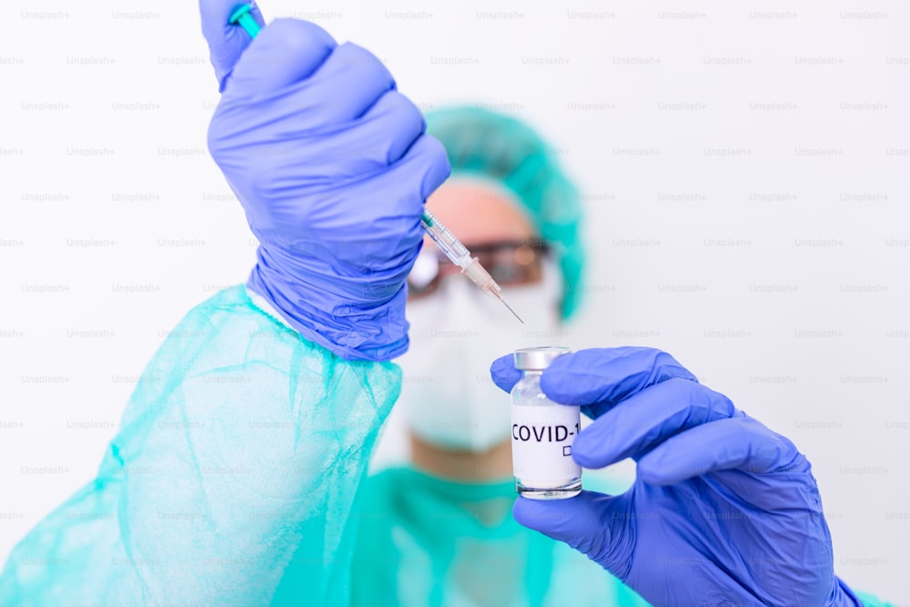 El médico, la enfermera o el científico se entregan con guantes de nitrilo azules que sostienen la vacuna contra la gripe, el sarampión, el coronavirus (COVID-19) para la vacunación de bebés y adultos, la medicina y el concepto de la droga