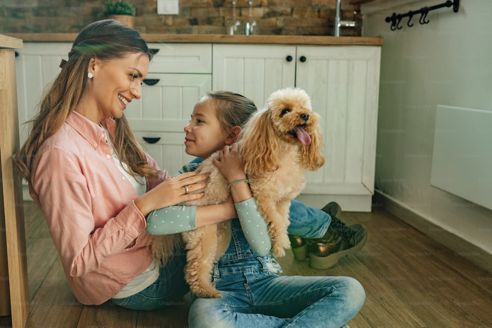 家で母親とコミュニケーションを取りながら犬を抱いている幸せな女の子。