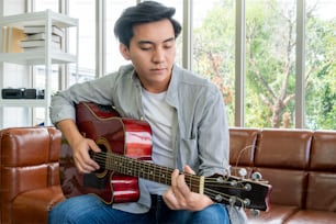 Joven guitarrista sosteniendo su guitarra en casa. Concepto de música y canción.
