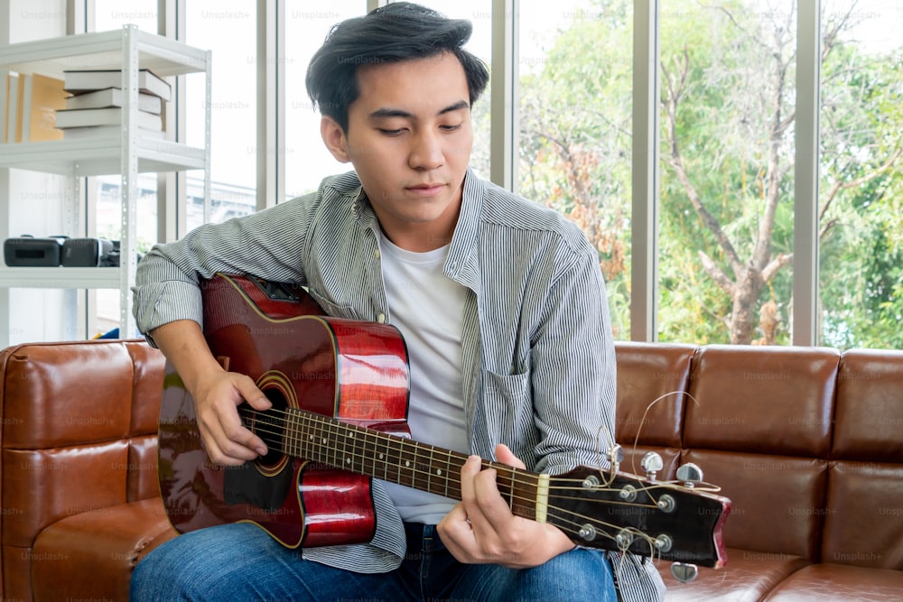 Young guitar player holding his guitar at home. Music and song concept.