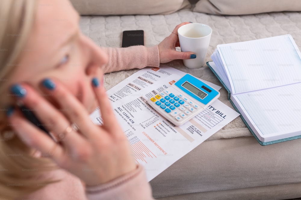 Bela jovem mulher Albino sentada com calculadora e contas, fazendo papelada. Mão mulher fazendo finanças e calcular na mesa sobre o custo em home office. Conceito de trabalho a partir de casa