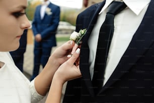 stylish gorgeous bride putting on  boutonniere on elegant groom at church ceremony