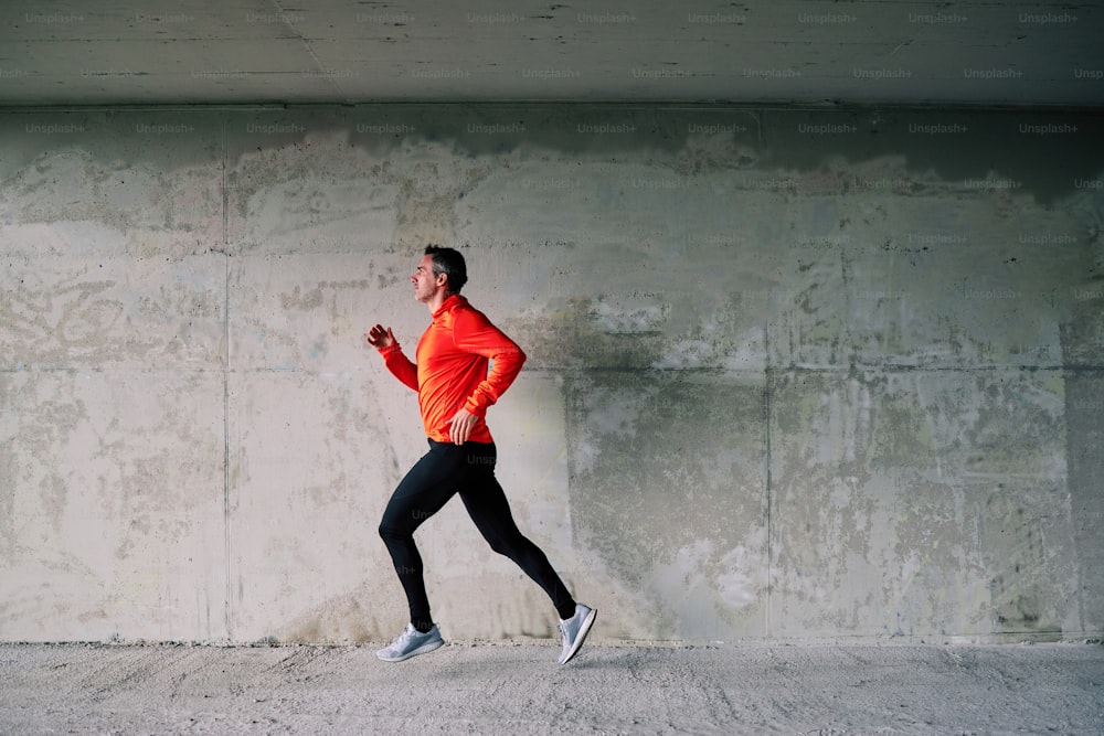 Side view of handsome sportsman running outdoors. Exercise alone.