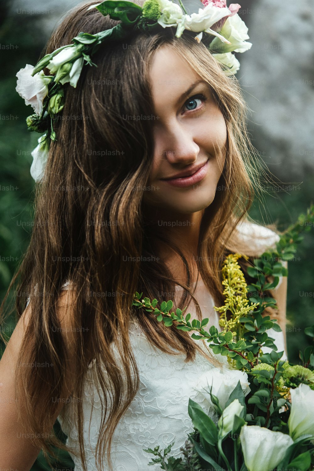 portrait stylish sensual bride in rustic wreath and with bouquet on background of rocks in mountains