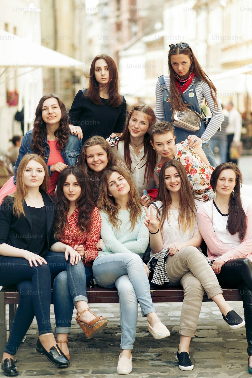 mulheres felizes elegantes hipsters moda vestido sorrindo e sentado no banco na rua da cidade da Europa, momentos alegres conceito de amizade