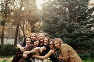 stylish elegant women having fun at celebration in sunny park, funny moment concept, gathering together