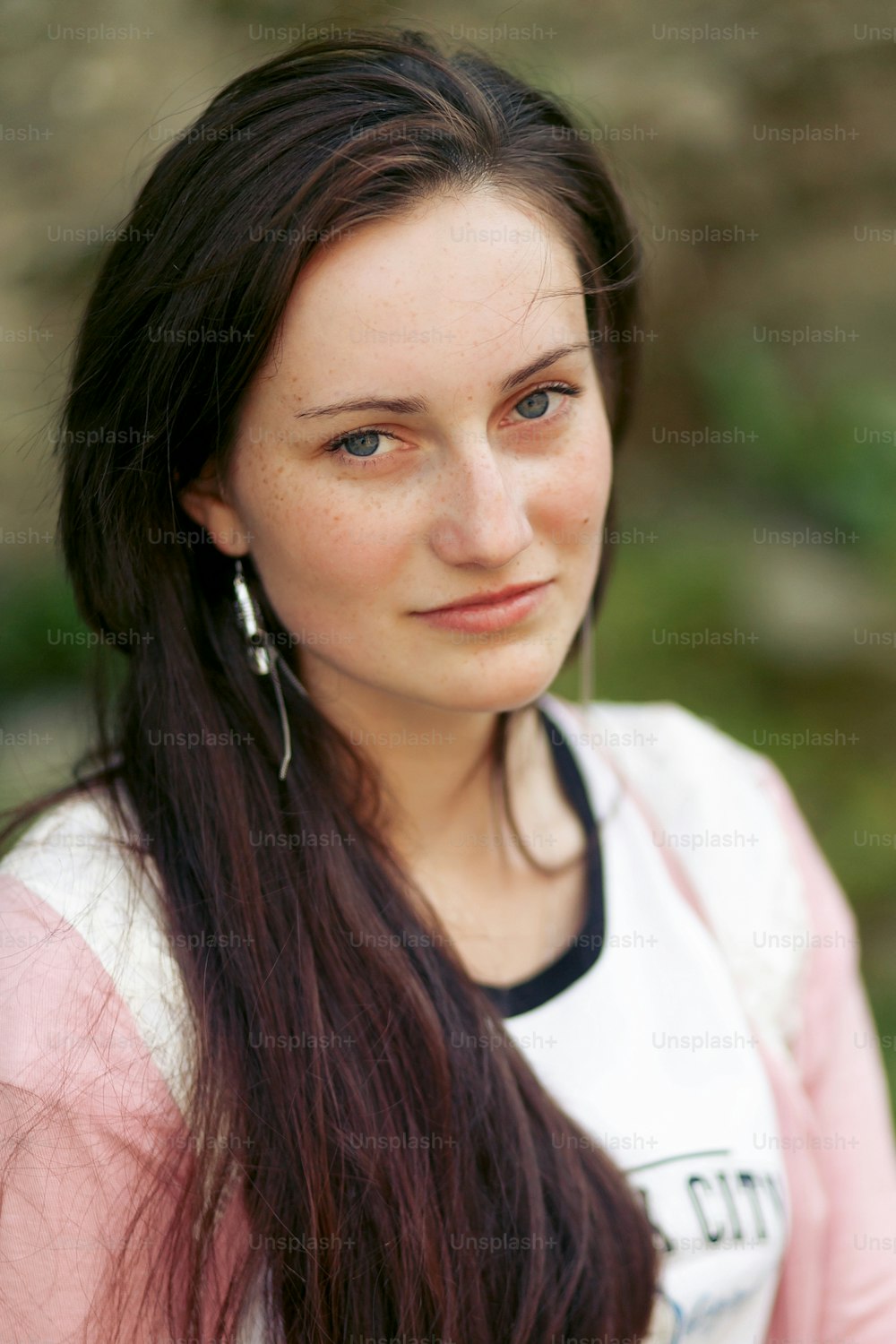 beautiful brunette girl posing and smiling in soft sunny light in city park in summer