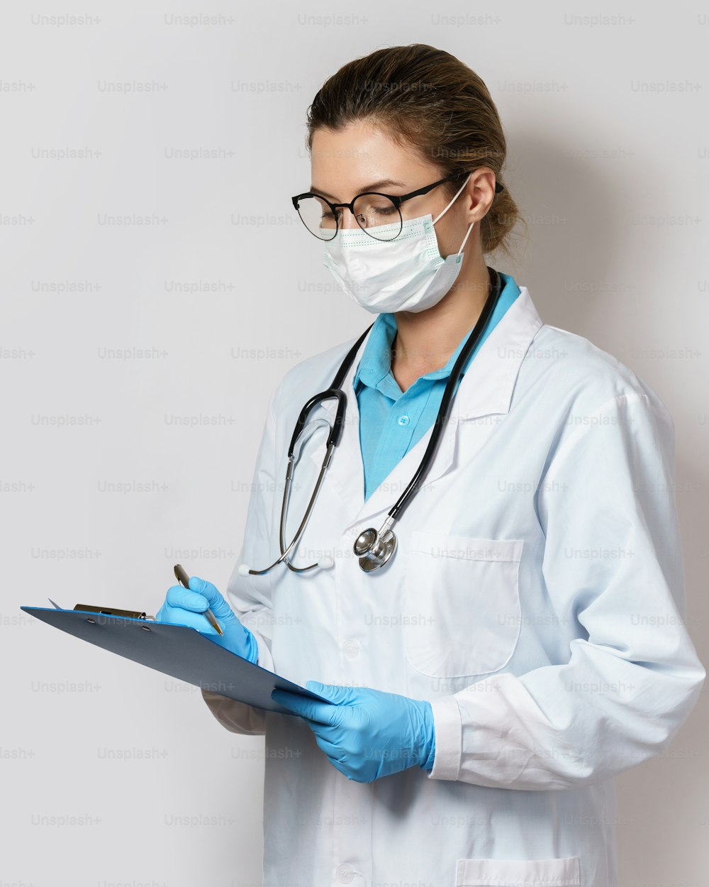 Young female doctor filling a report on gray background