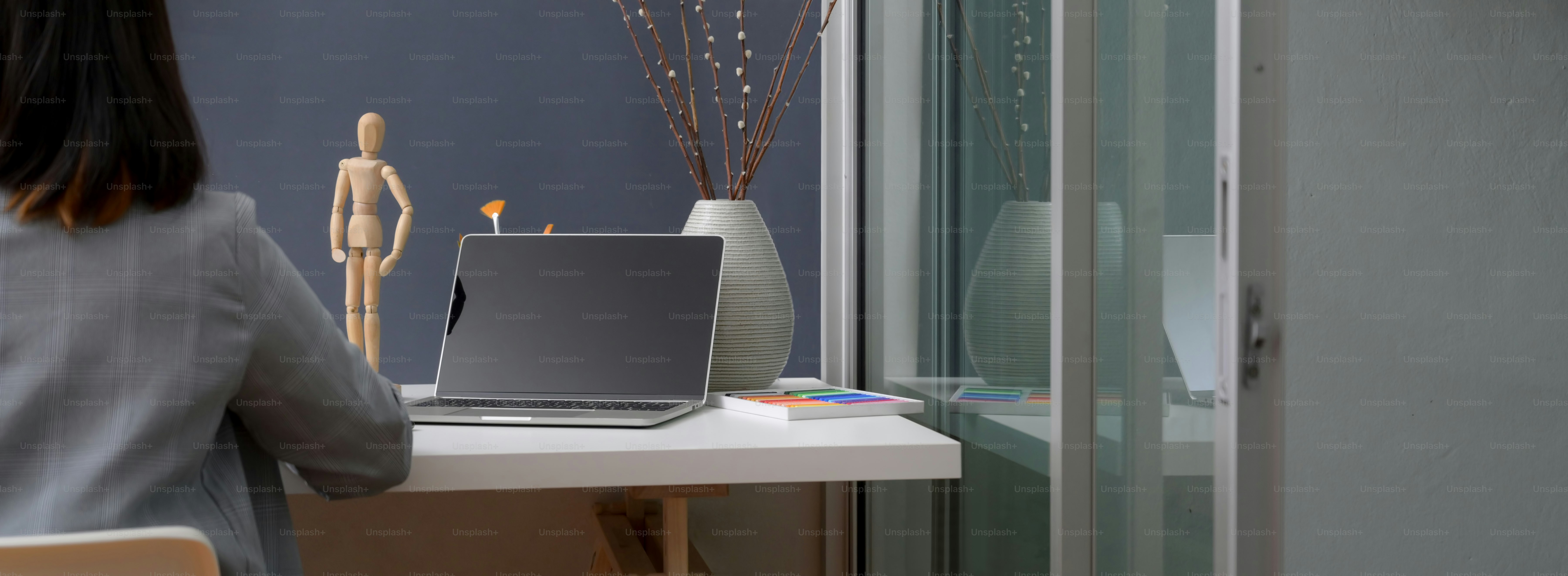 Cropped shot of professional designer working in trendy office room with laptop and designer supplies on white table