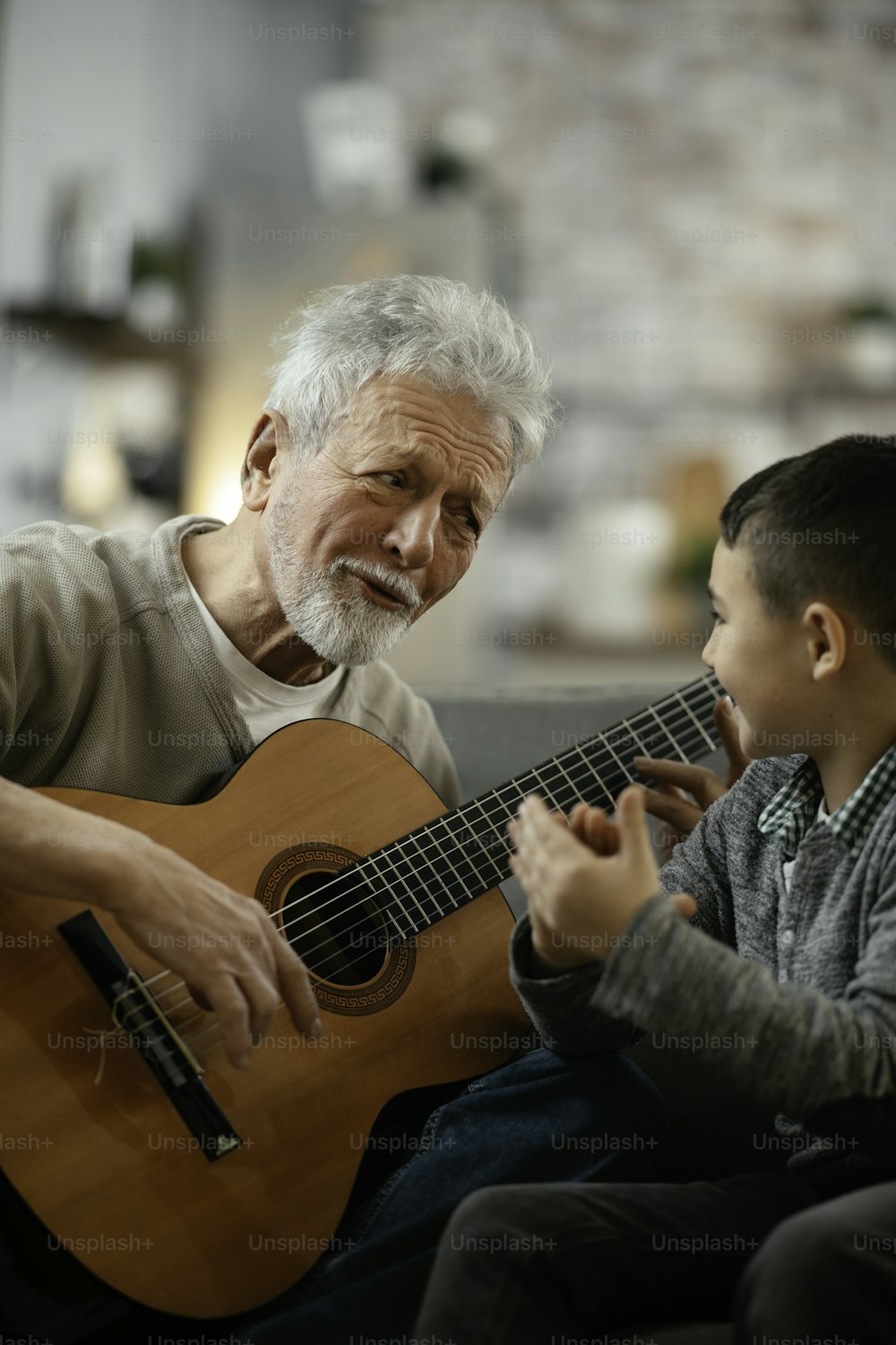 할아버지와 손자가 기타를 연주하고 있다. 할아버지와 손자가 집에서 놀고 있다.
