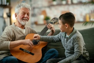 Großvater und Enkel spielen Gitarre. Großvater und Enkel gemütlich zu Hause.