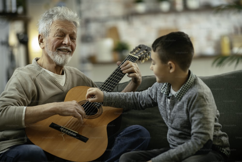 Grandfather and grandson playing guitar. Grandfather and grandson enyoing at home.