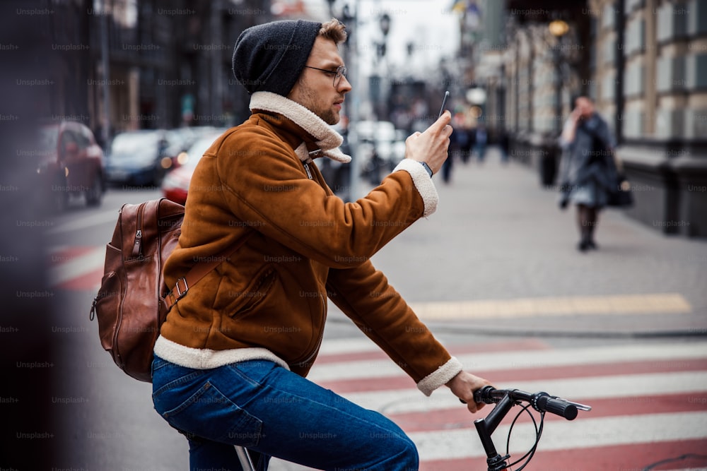 Ernsthafter Tourist auf einem Fahrrad schaut auf den Smartphone-Bildschirm auf der Straße und runzelt die Stirn