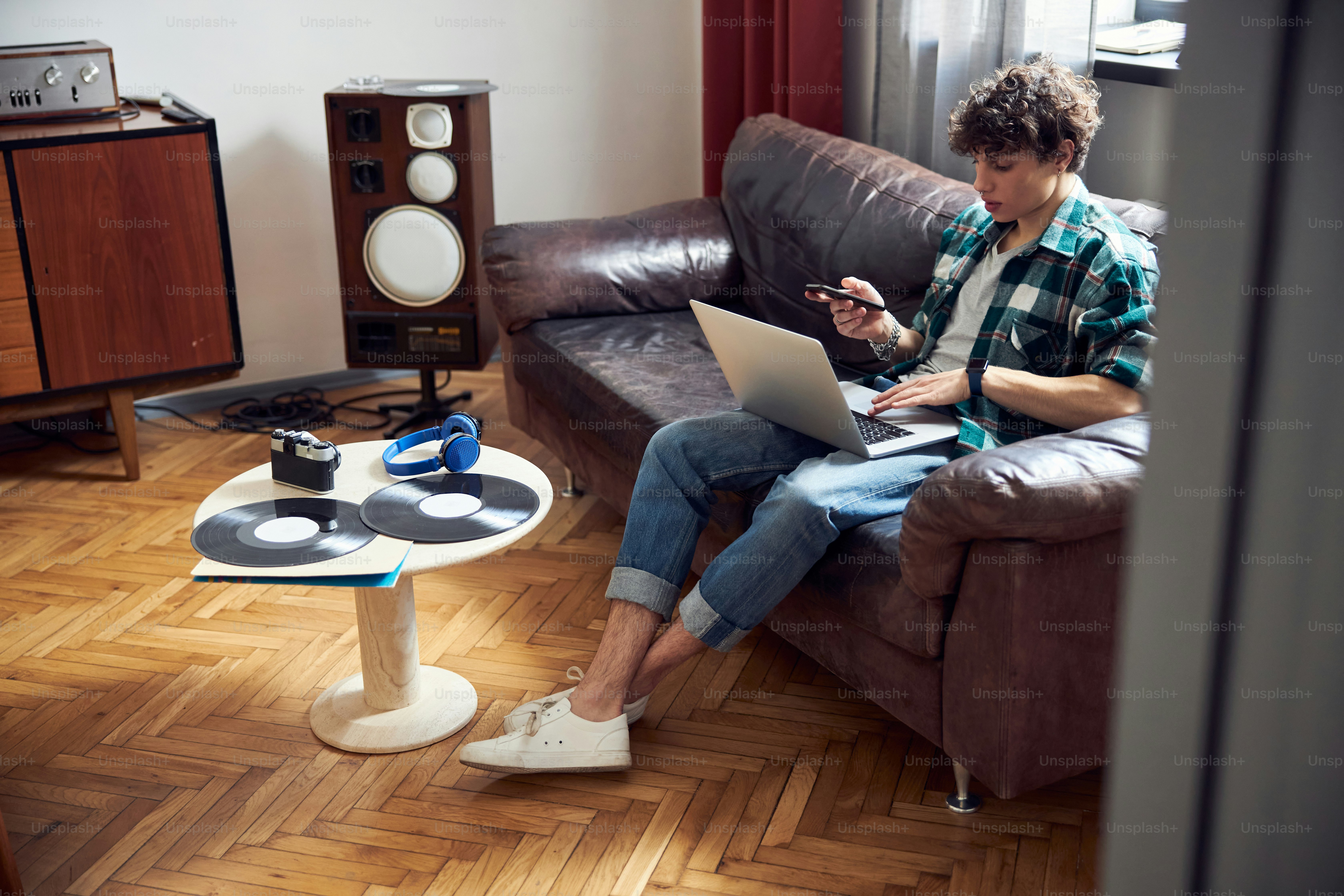 Stylish guy holding smartphone and surfing the internet on notebook stock photo